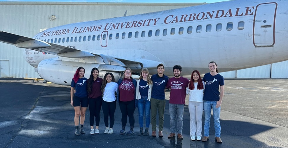 group photo of the National Gay Pilots Association members in front of a plane